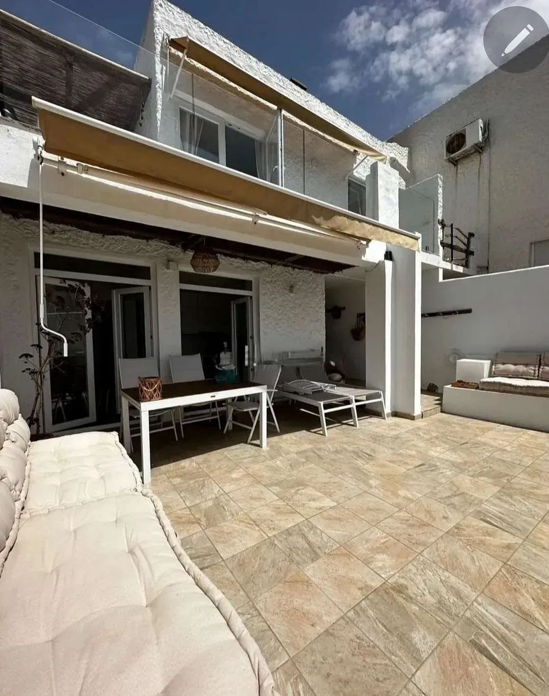 Una casa grande de color blanco con un patio con mesa y sillas.