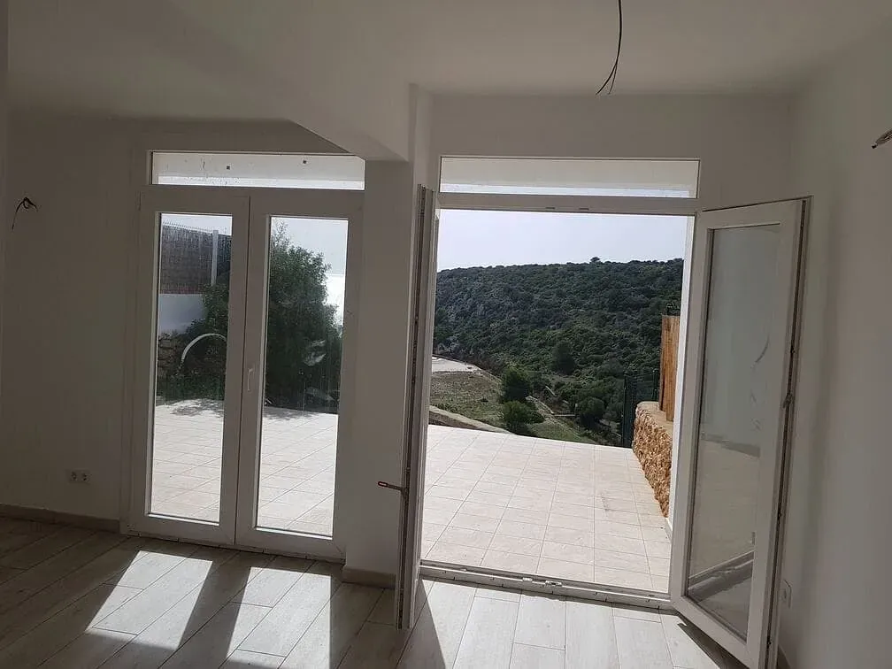 Una habitación con muchas ventanas y vista a un bosque.