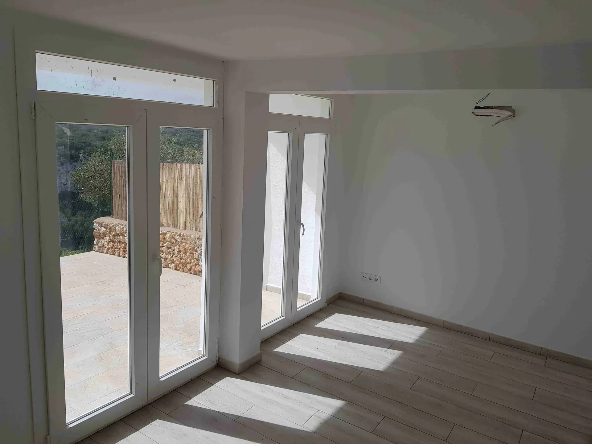 Una habitación vacía con muchas ventanas y suelo de madera.