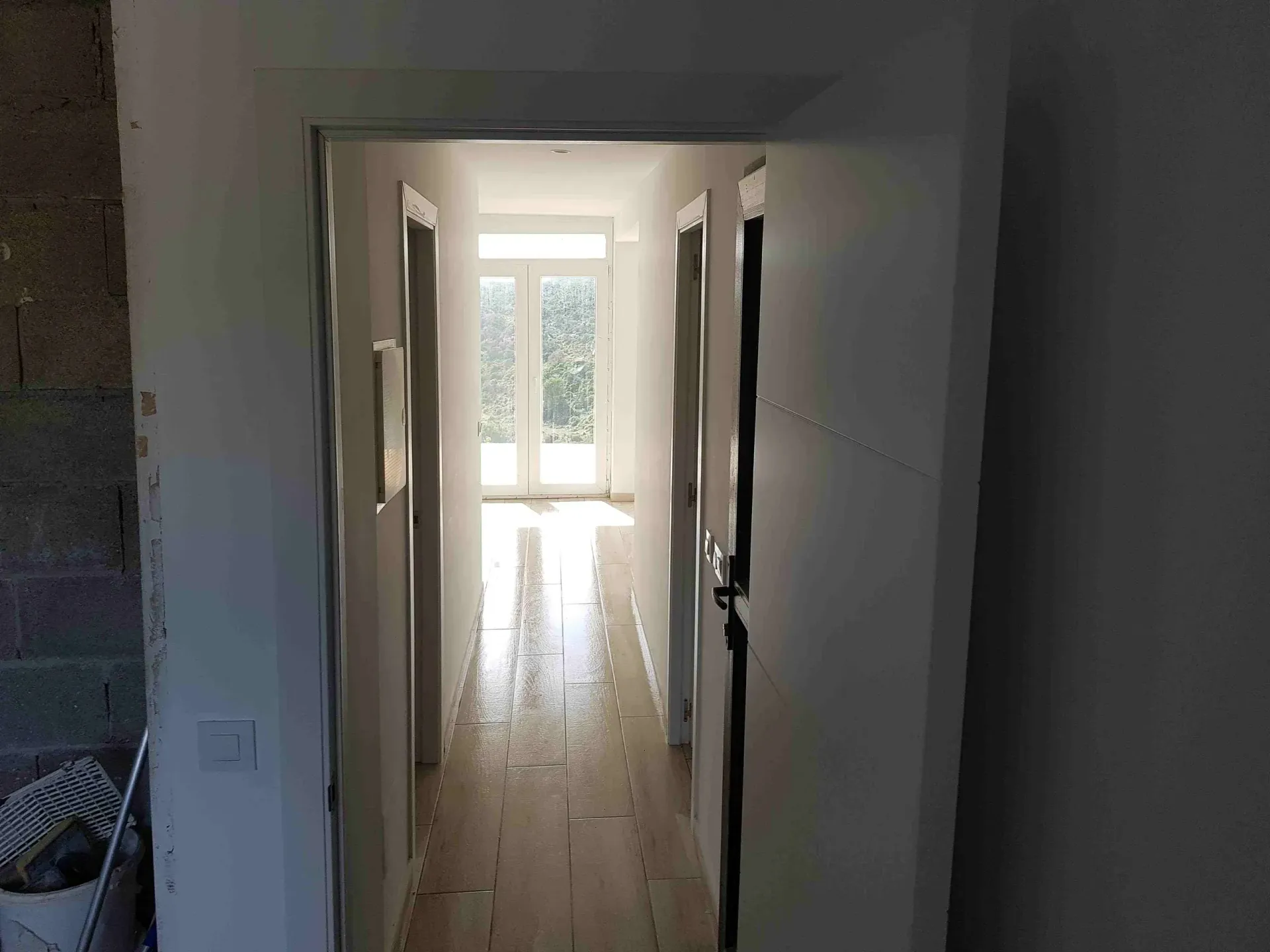 Un largo pasillo con paredes blancas y pisos de madera en una casa en construcción.