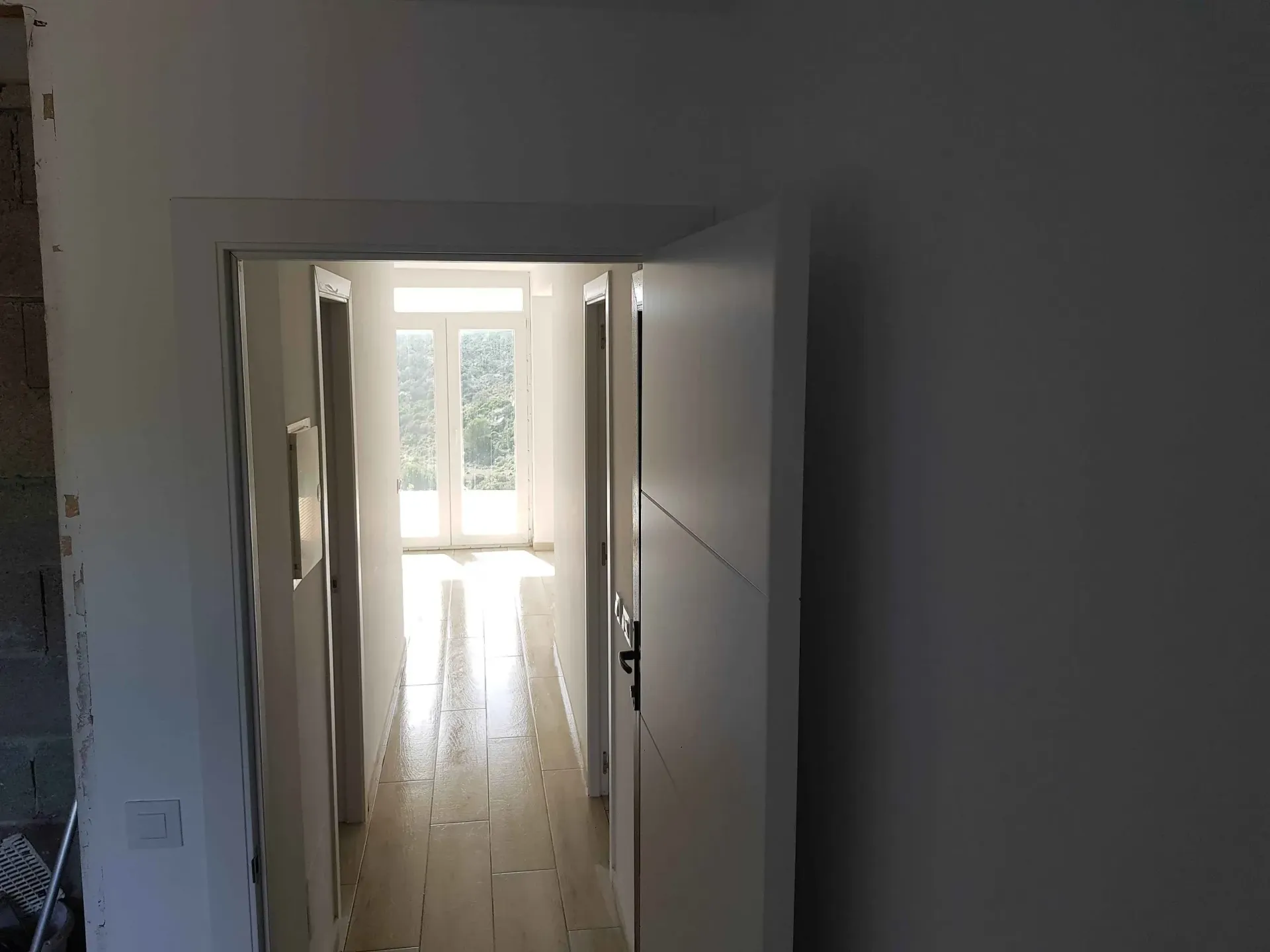 Un largo pasillo con suelo de madera y paredes blancas.