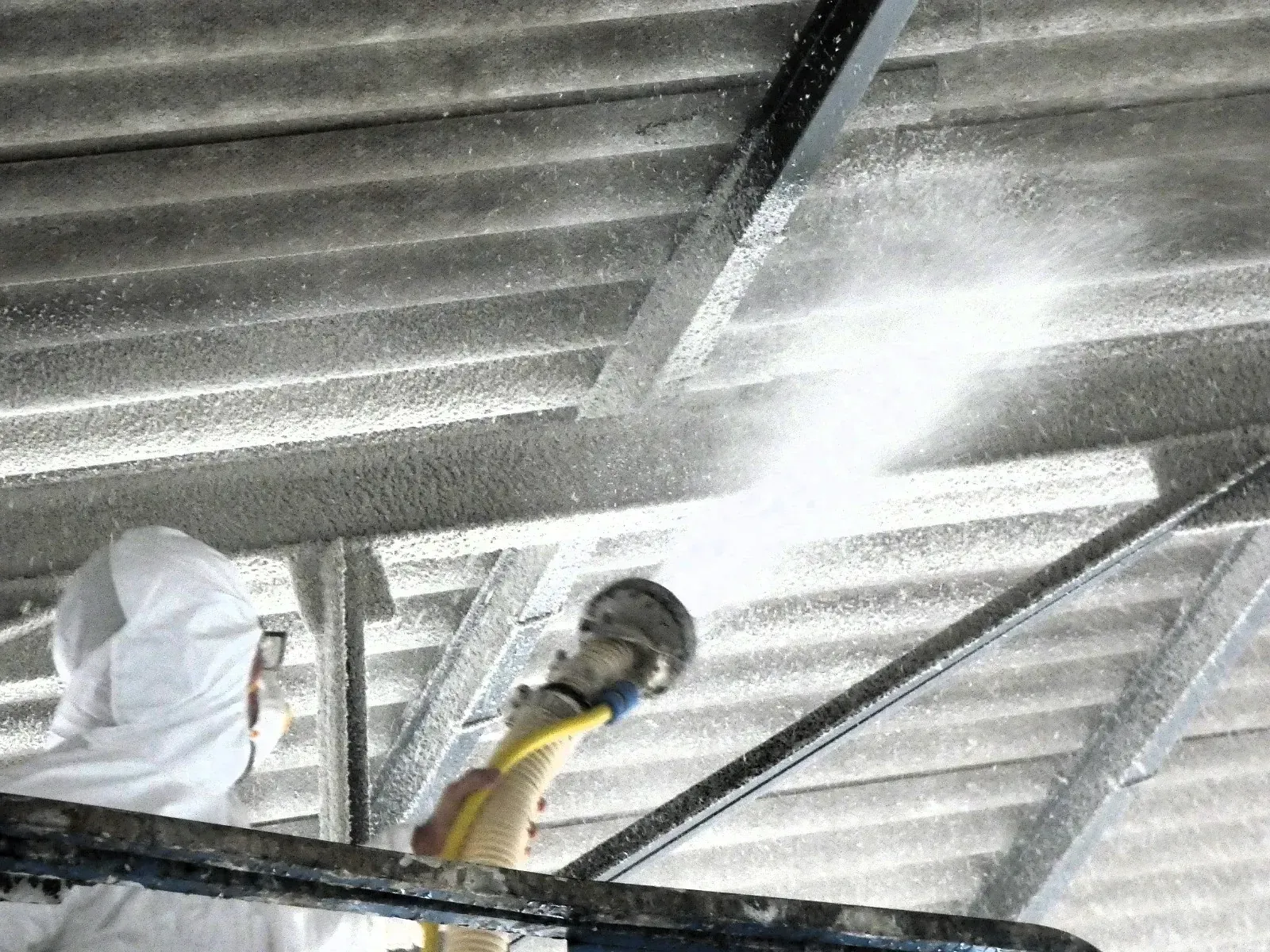 Un hombre está rociando un techo con una manguera.