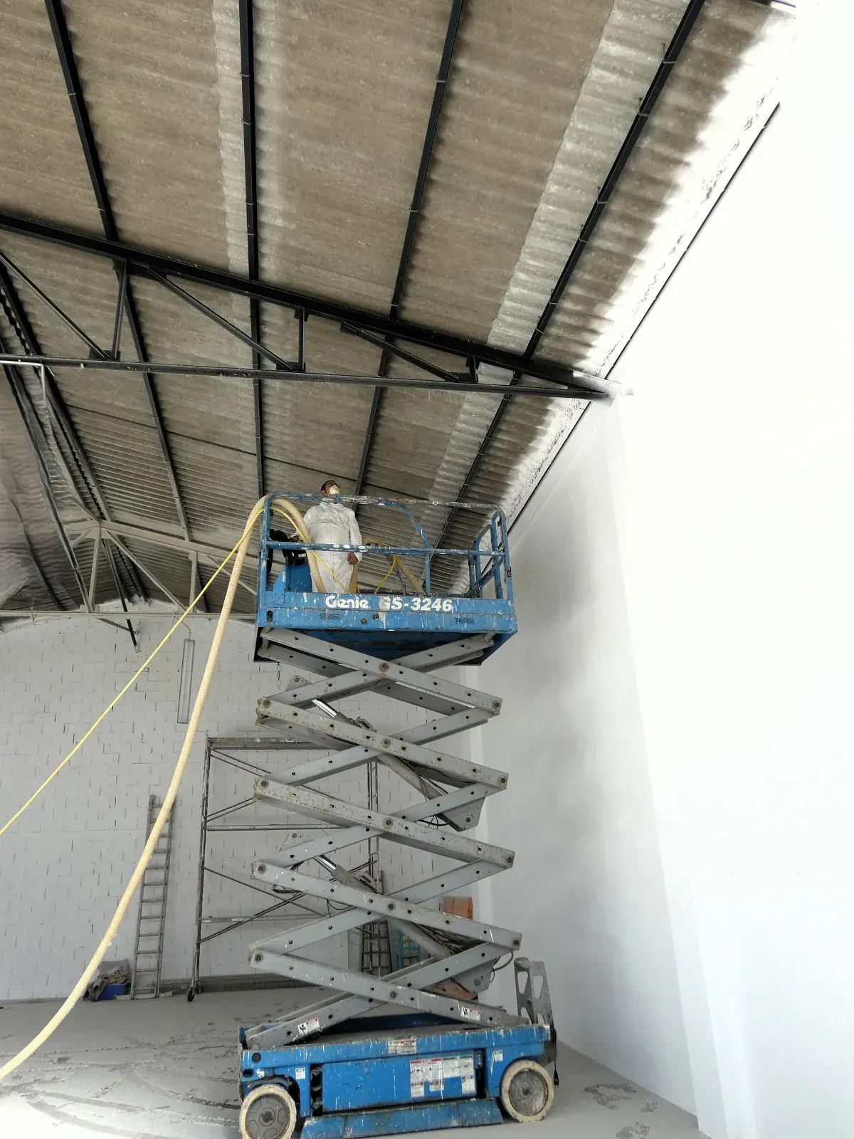 Un hombre está trabajando en un elevador de tijera en un almacén.