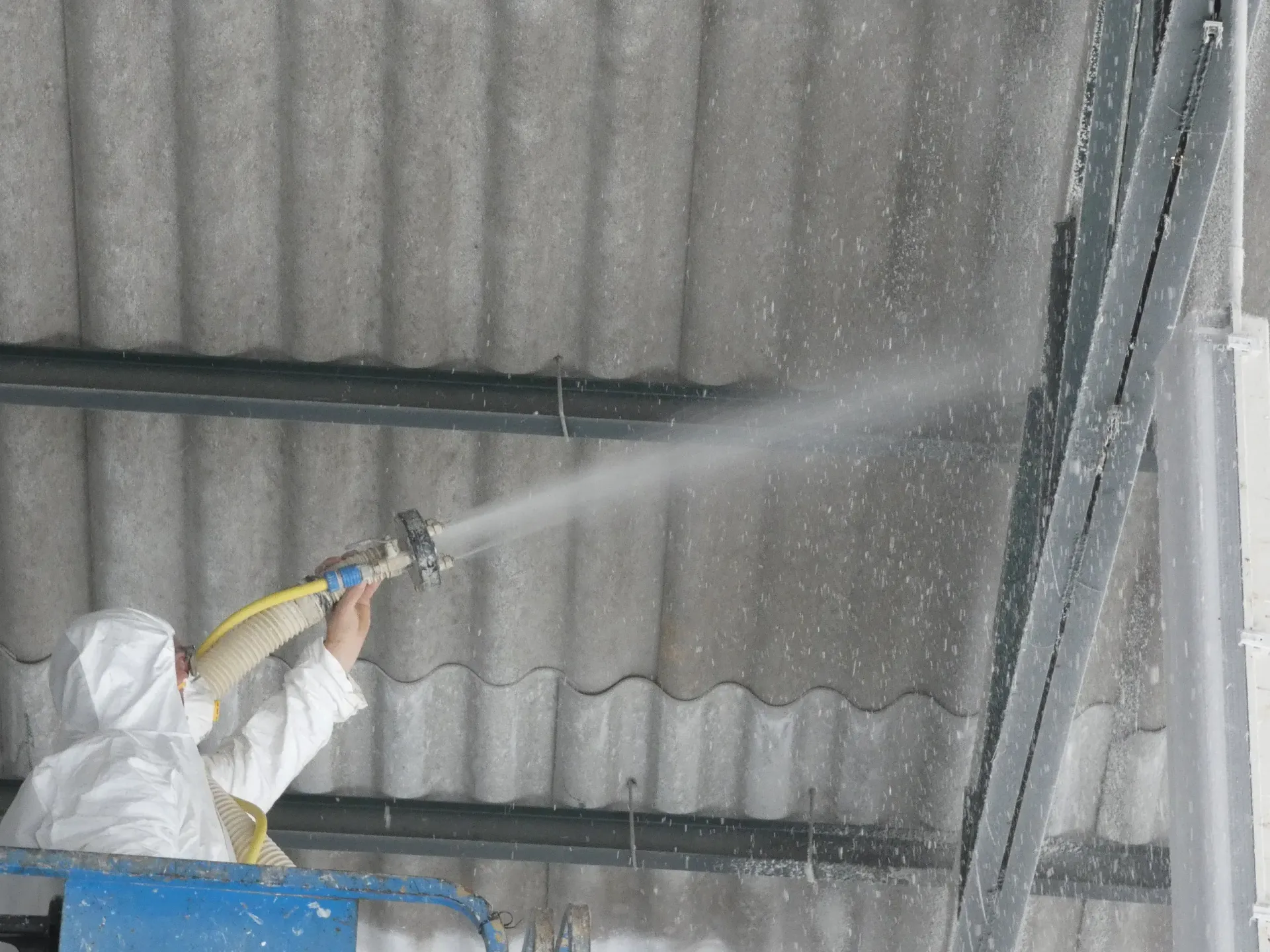 Un hombre está rociando un techo con una manguera.