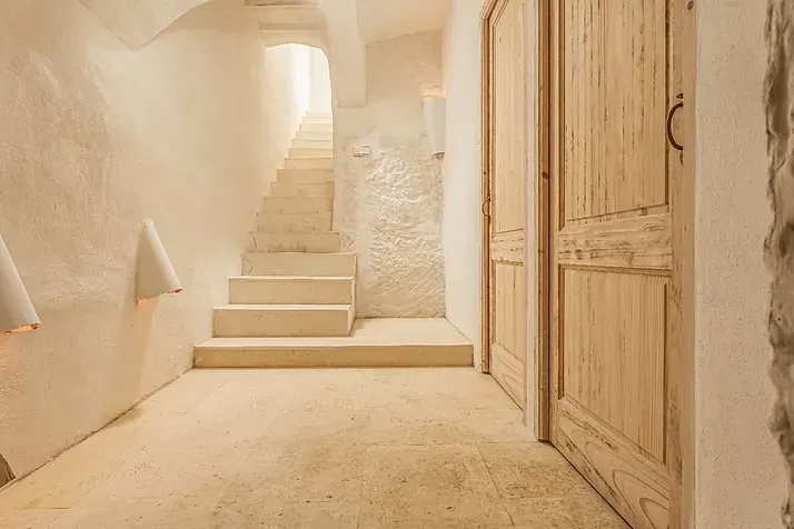 Un pasillo con escaleras y puertas de madera en una casa.