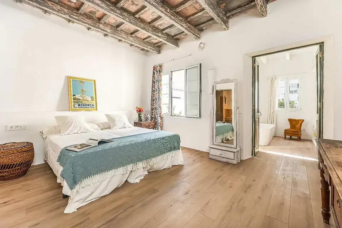 Un dormitorio con una cama grande y suelo de madera.