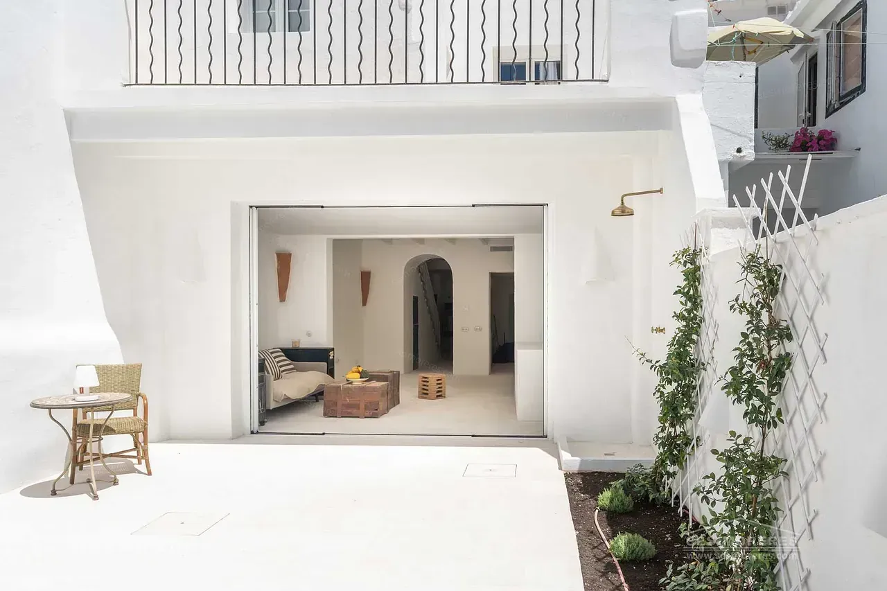 Un edificio blanco con un balcón y una mesa y sillas delante.