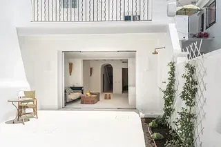 Una casa blanca con un balcón y una mesa y sillas afuera.