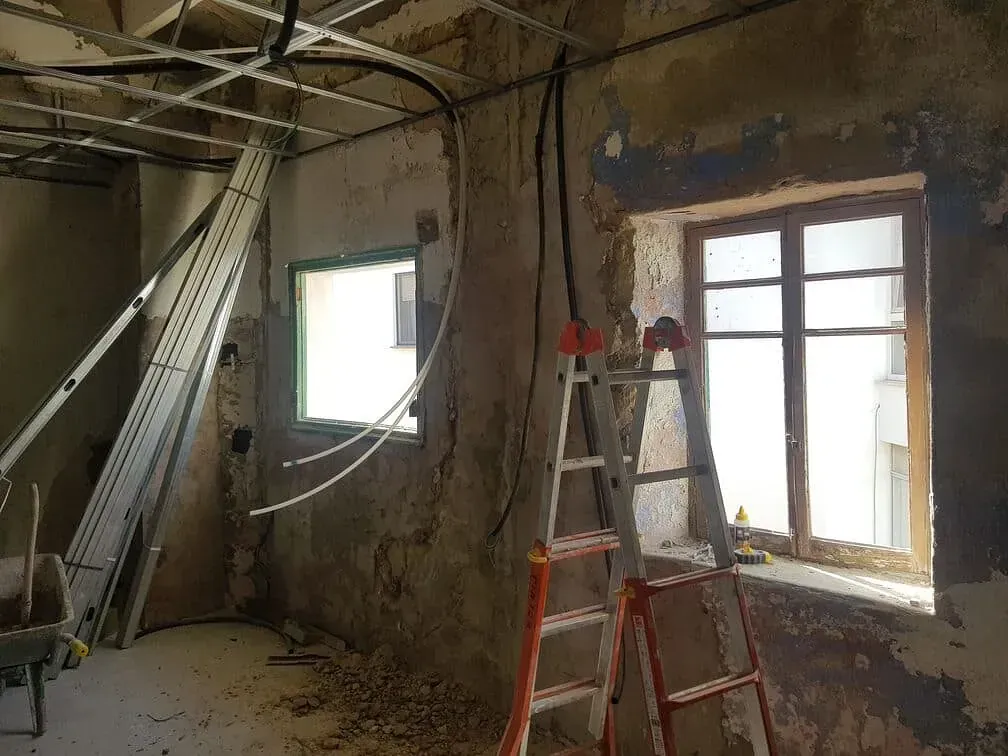 Una escalera está en una habitación al lado de una ventana.