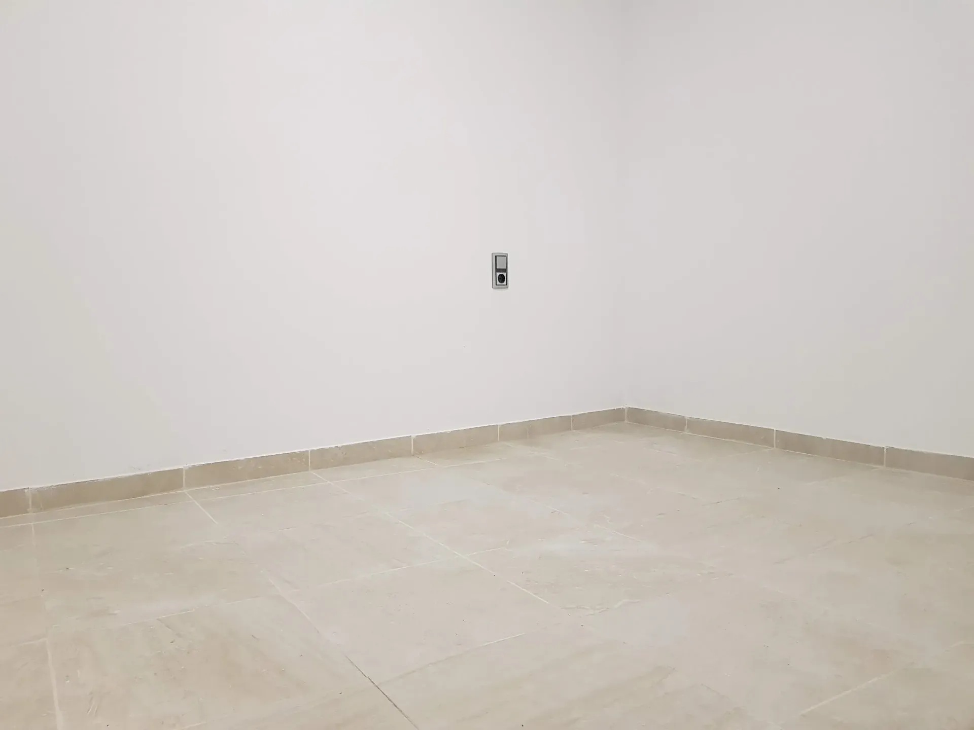 Una habitación vacía con suelo de baldosas y paredes blancas.