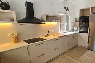 Una cocina con gabinetes blancos y electrodomésticos de acero inoxidable.