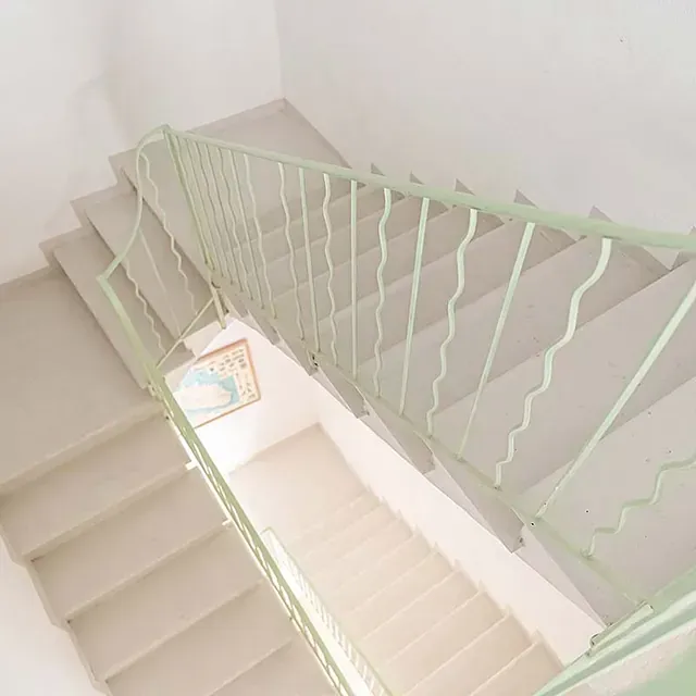 Un conjunto de escaleras con una barandilla verde y un cuadro en la pared.