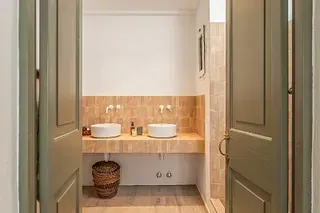 Un baño con dos lavabos y una puerta verde.
