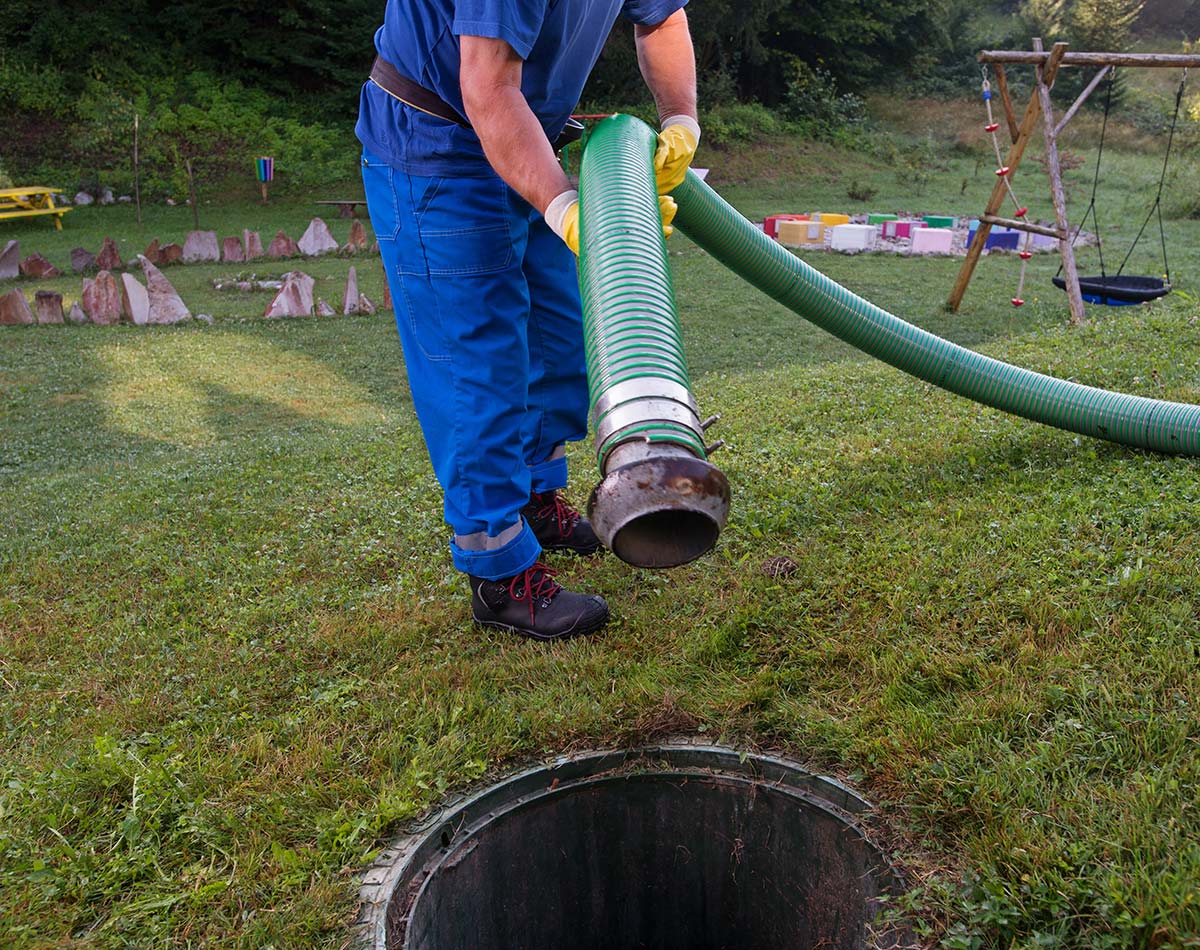 Employé soulevant un tuyau servant à la vidange d'une fosse septique