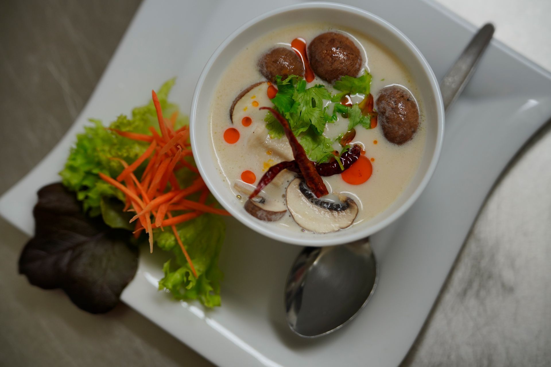 Suppe mit Pilzen Eine Schüssel Suppe mit Pilzen und Gemüse auf einem Teller mit einem Löffel.