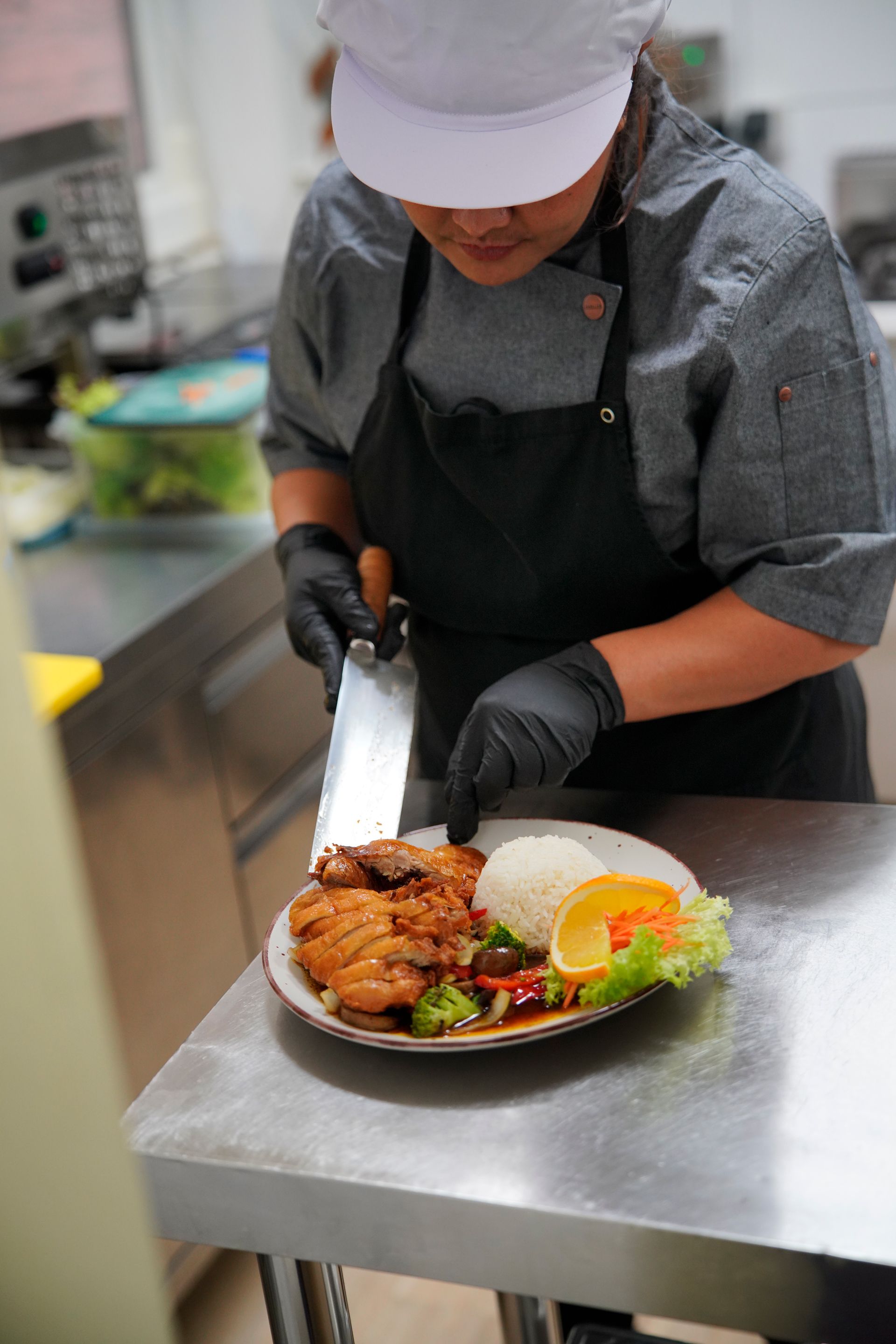Ein Koch bereitet in einer Küche einen Teller mit Essen zu.
