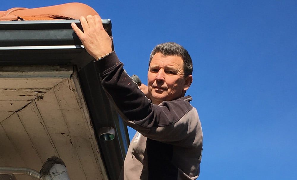 Professionnel regardant l'objectif une main posée sur une gouttière