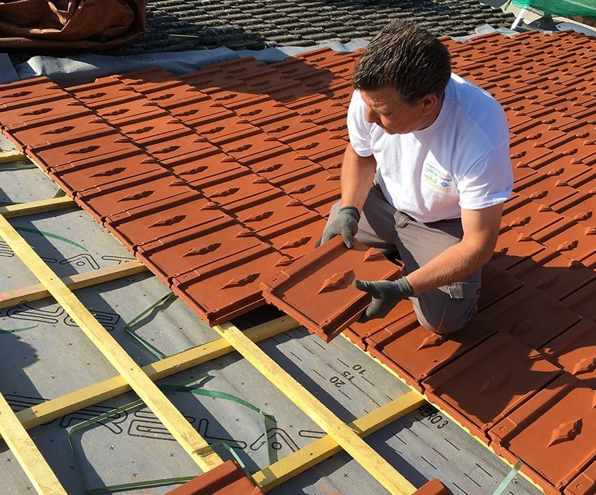 Artisan remplaçant des tuiles sur un toit