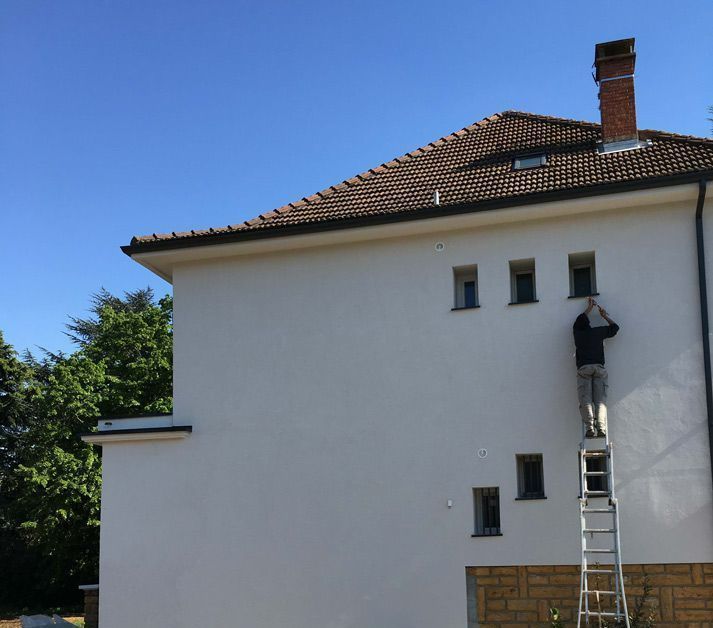 Homme debout sur une échelle contre la façade d'une maison