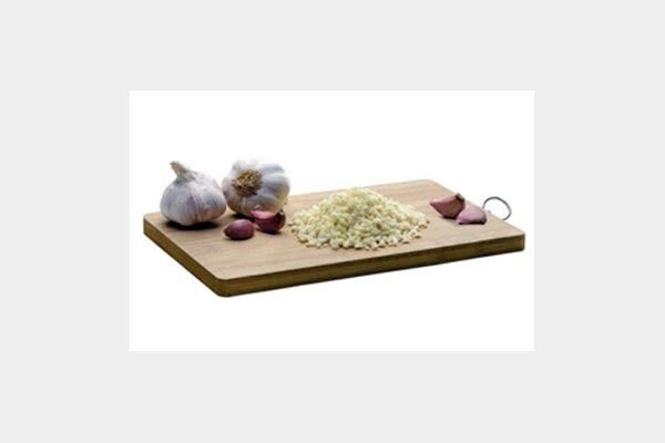 Una tabla de cortar de madera con ajo y cebollas encima.