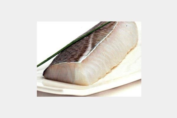 Un trozo de pescado está sentado en un plato blanco.