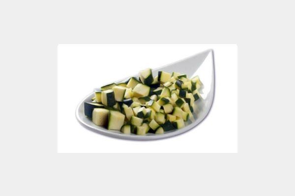 Un plato blanco cubierto con calabacín picado sobre un fondo blanco.