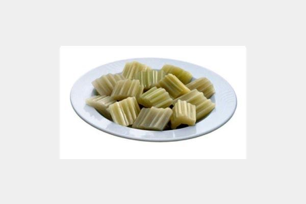 Un plato blanco cubierto con rodajas de apio sobre un fondo blanco.