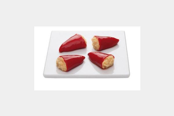 Cuatro pimientos rojos rellenos en un plato blanco
