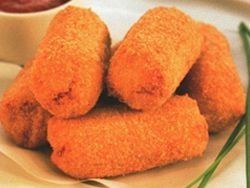 Un montón de palitos de comida frita en un plato al lado de un tazón de salsa de tomate.