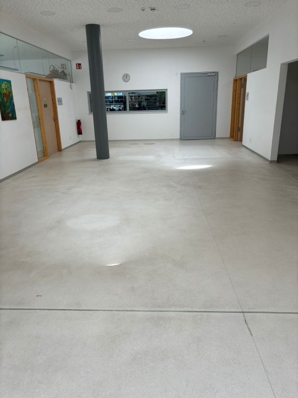 Ein leerer, heller Flur mit einem zentralen Stützpfeiler. Türen