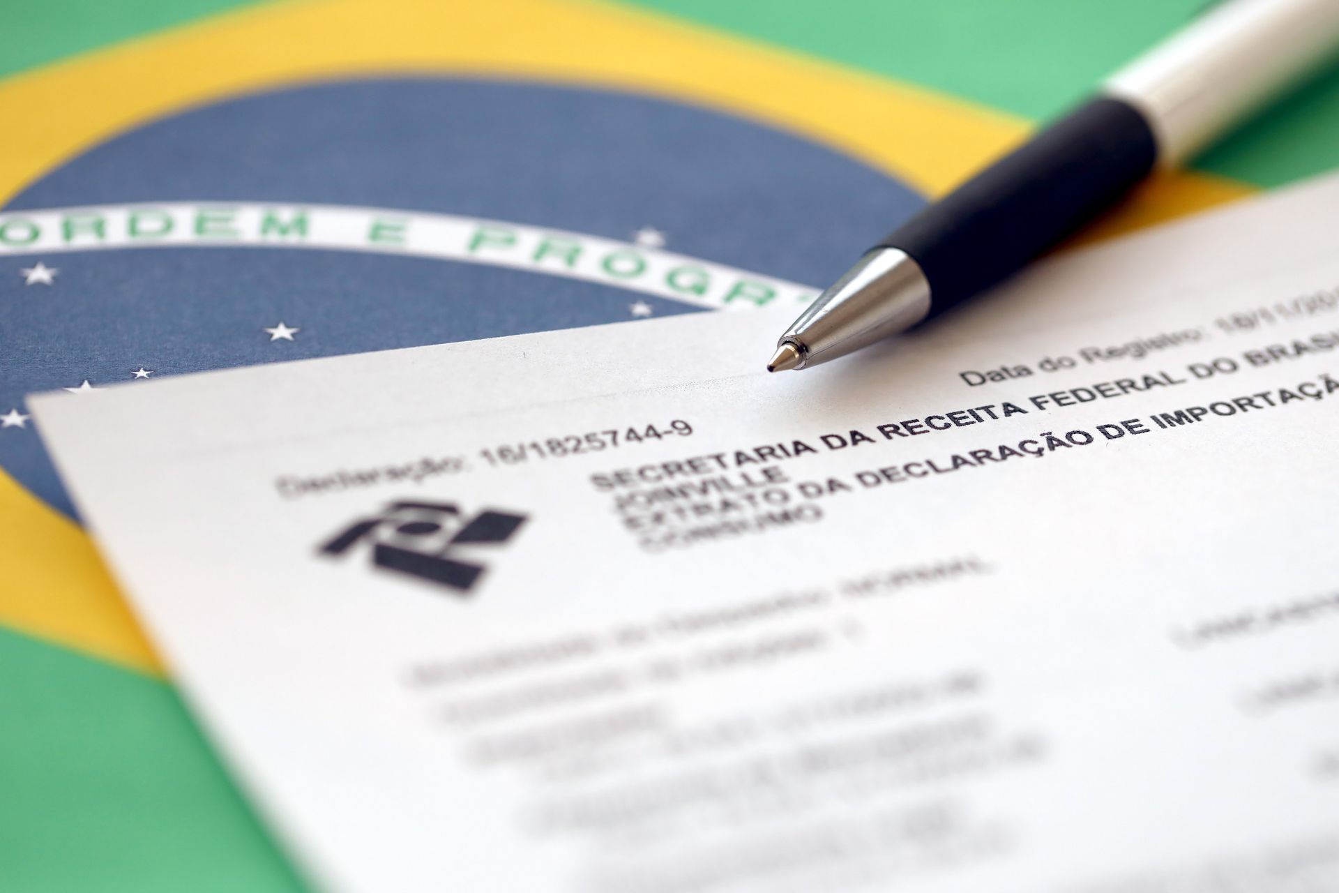 Un bolígrafo reposa sobre un trozo de papel que dice ordem e progress