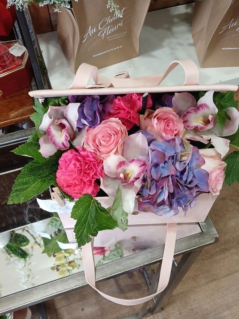 Bouquet de fleurs roses et violettes dans un sac cadeau rose pâle sur une étagère