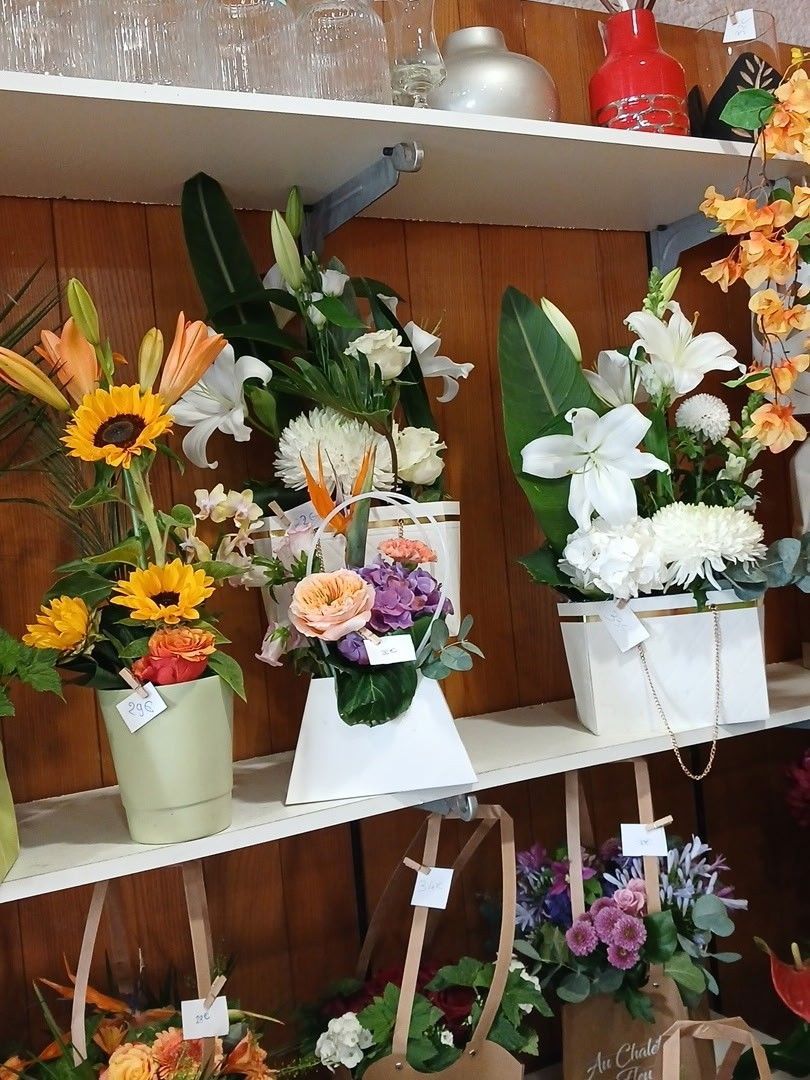 Des compositions florales colorées variées sont présentées sur les étagères d'un magasin.