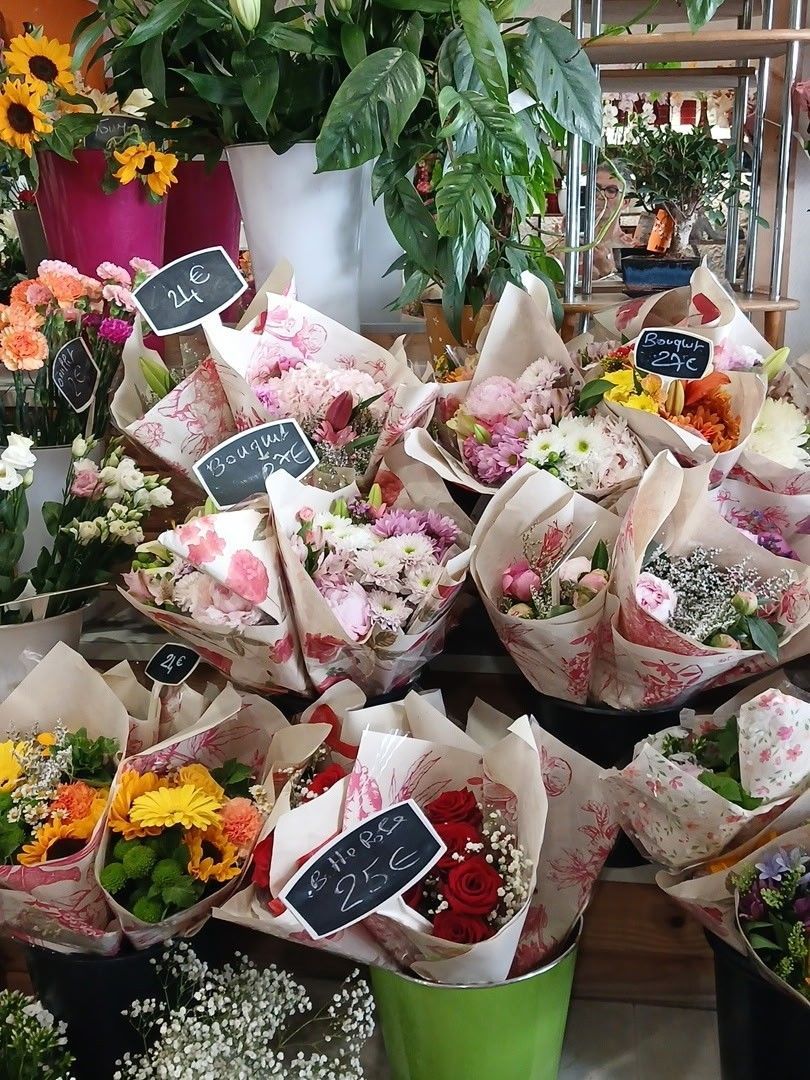 Bouquets de fleurs variées emballés dans du papier, exposés dans une boutique de fleurs avec des panneaux à ardoise