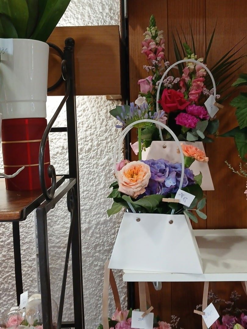Des fleurs dans des boîtes cadeaux blanches et rouges sur une étagère, avec un vase et un fond en bois à l'intérieur.