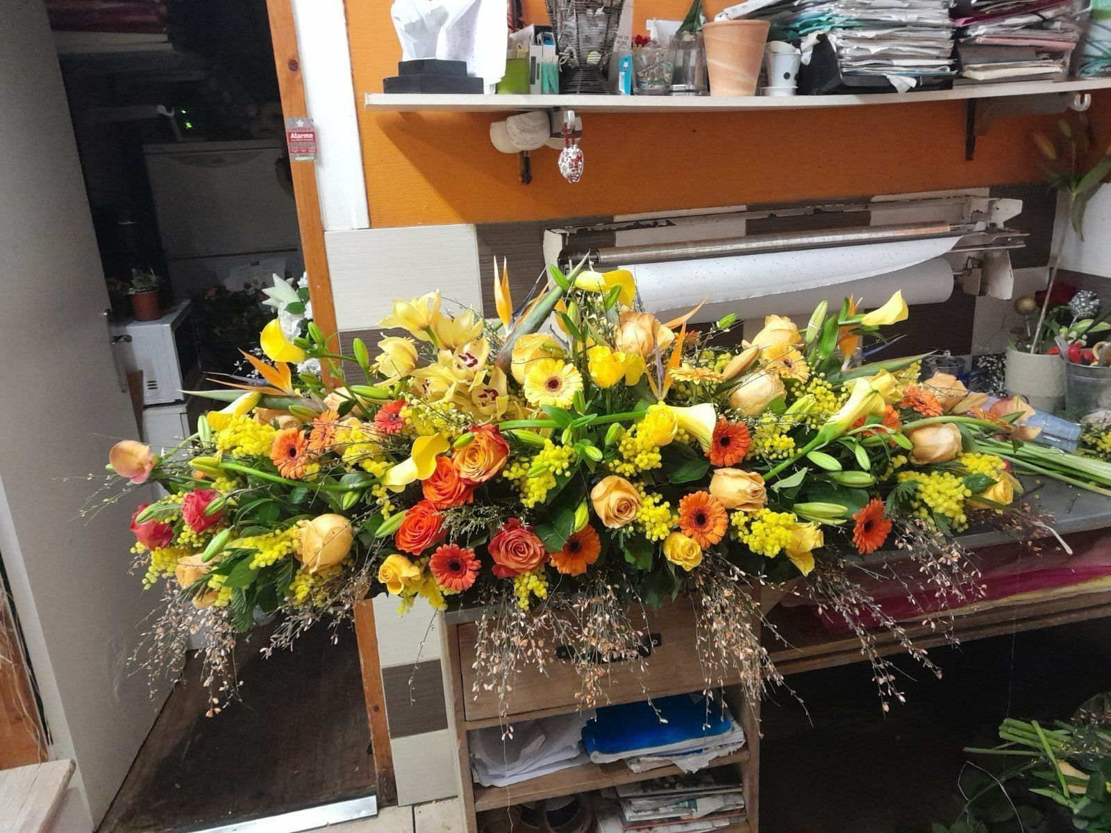 Dessus de cercueil composé de fleurs jaunes et oranges