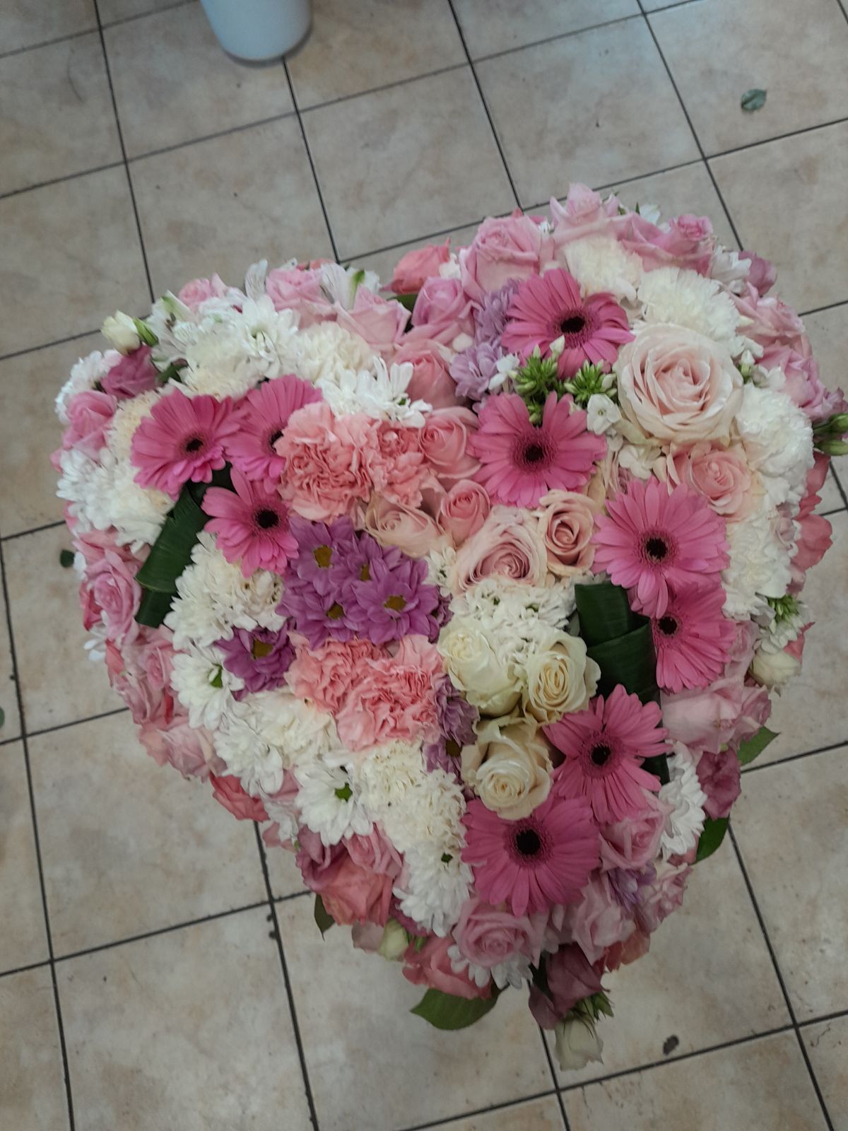 Coussin de deuil composé de fleurs roses, violettes et blanches
