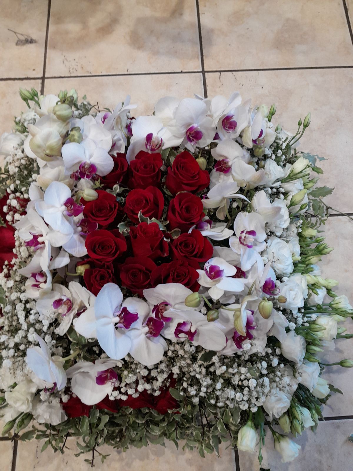 Carré pour le cercueil avec un centre de roses rouges entouré de fleurs blanches