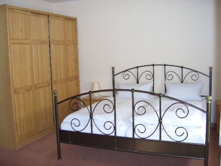 Verschnörkeltes Bett mit weißer Bettwäsche