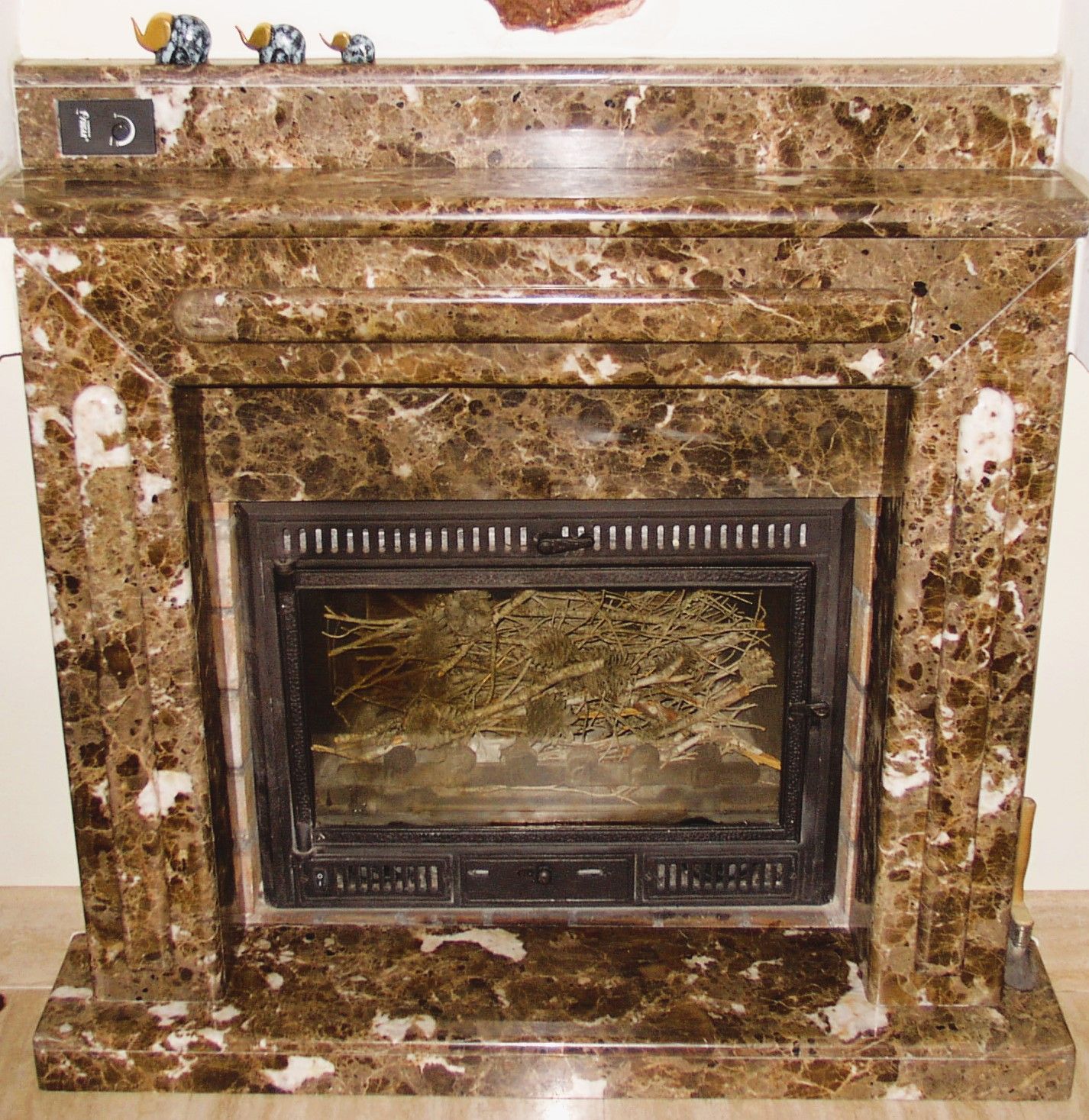 Una chimenea de mármol marrón y blanco con un reloj en la parte superior.