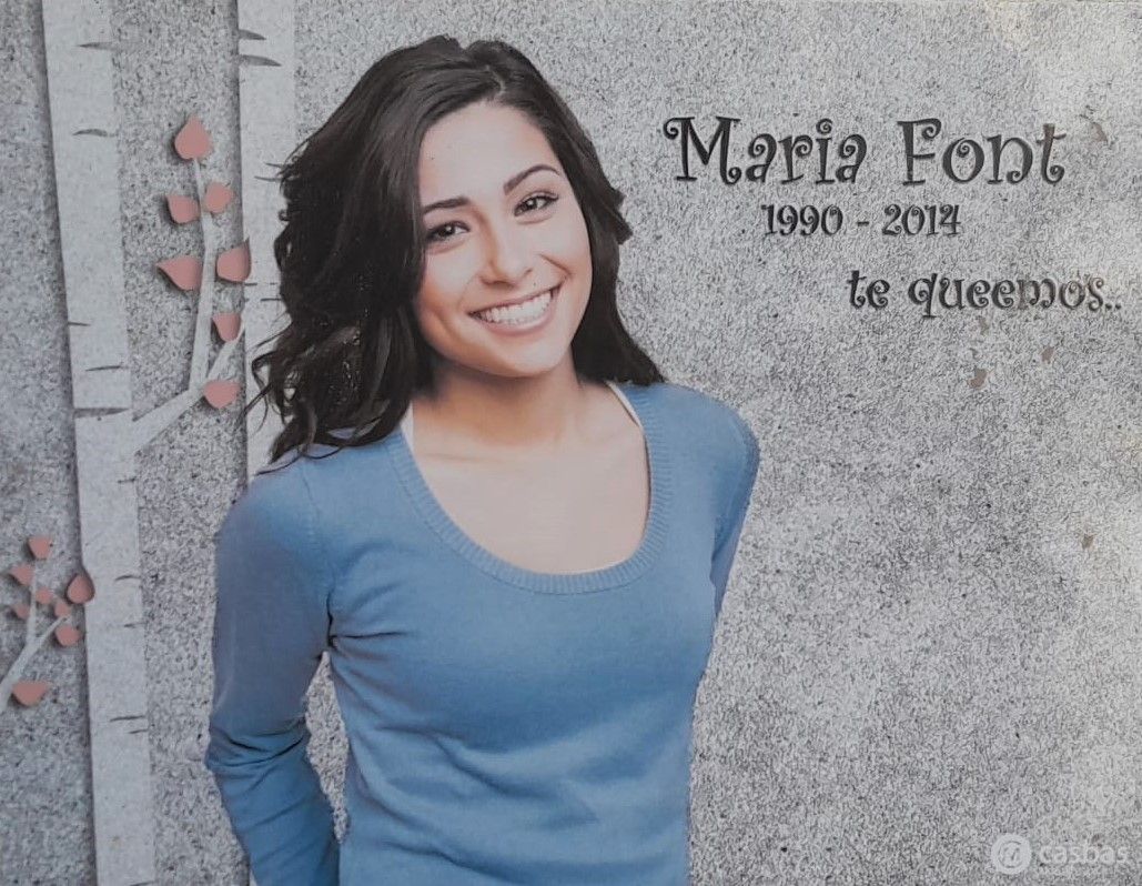 Una mujer con una camisa azul sonríe frente a una pared que dice María Font.