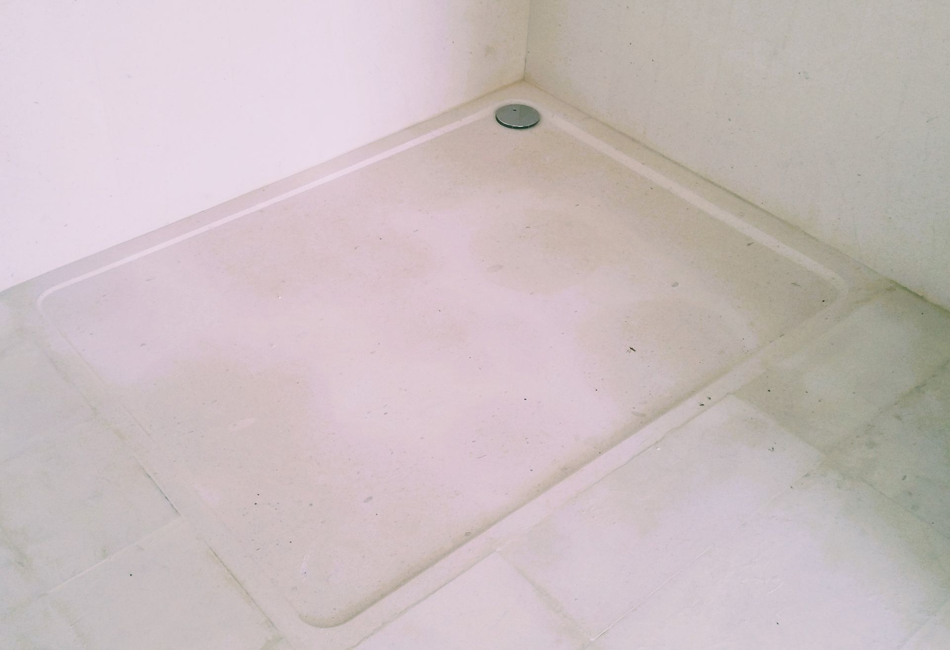 Una cabina de ducha en un baño con desagüe en el suelo.