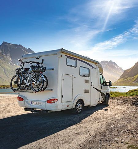 Weißes Wohnmobil mit Fahrrädern auf einem Gepäckträger.