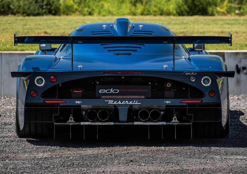 Rückansicht eines blauen Sportwagens mit großem Spoiler und Doppelauspuff. „Rebellion“-Schriftzug sichtbar.