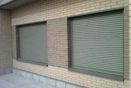 Un edificio de ladrillo con dos ventanas con contraventanas.