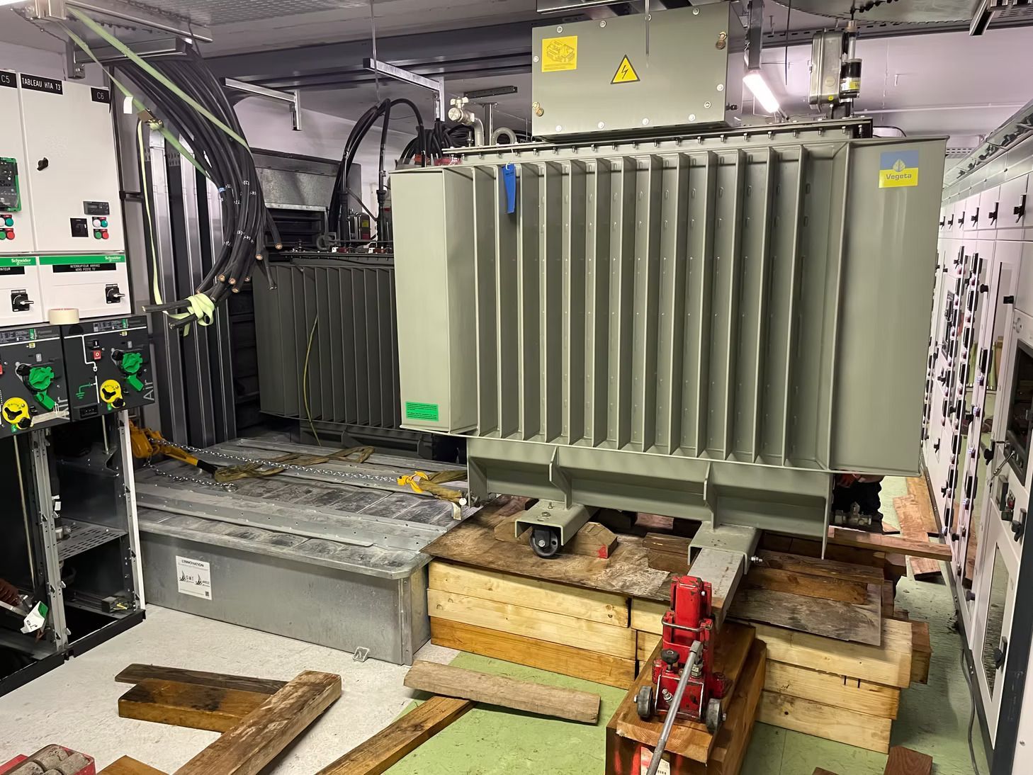 Machine industrielle équipée d’un gros transformateur gris, posée sur une palette en bois dans un atelier ou une usine