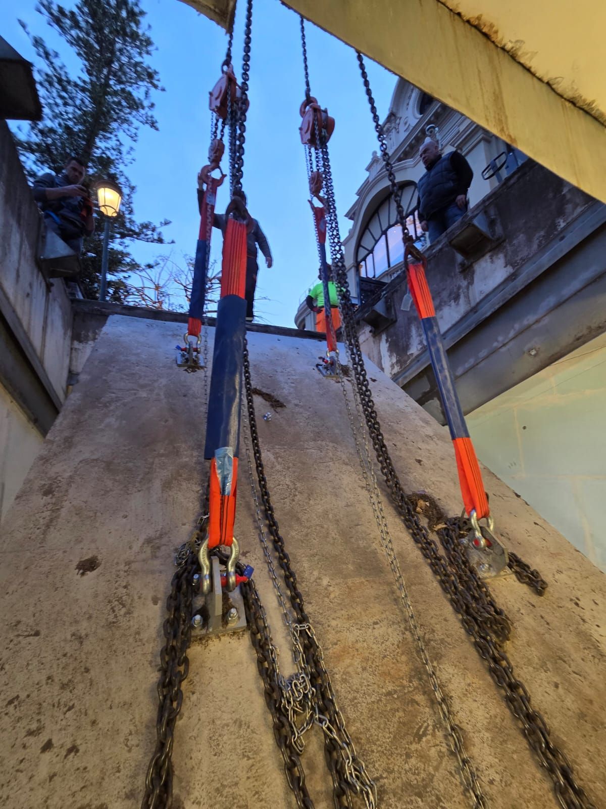 Équipe de secours sur corde descendant un puits de béton escarpé, équipée de harnais et de matériel de sécurité orange vif
