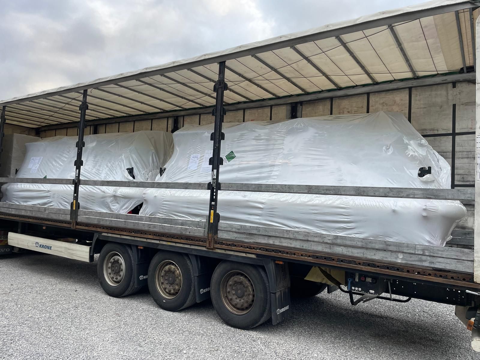 Grand bateau blanc enveloppé de plastique sur une remorque porte-bateau sous un abri couvert