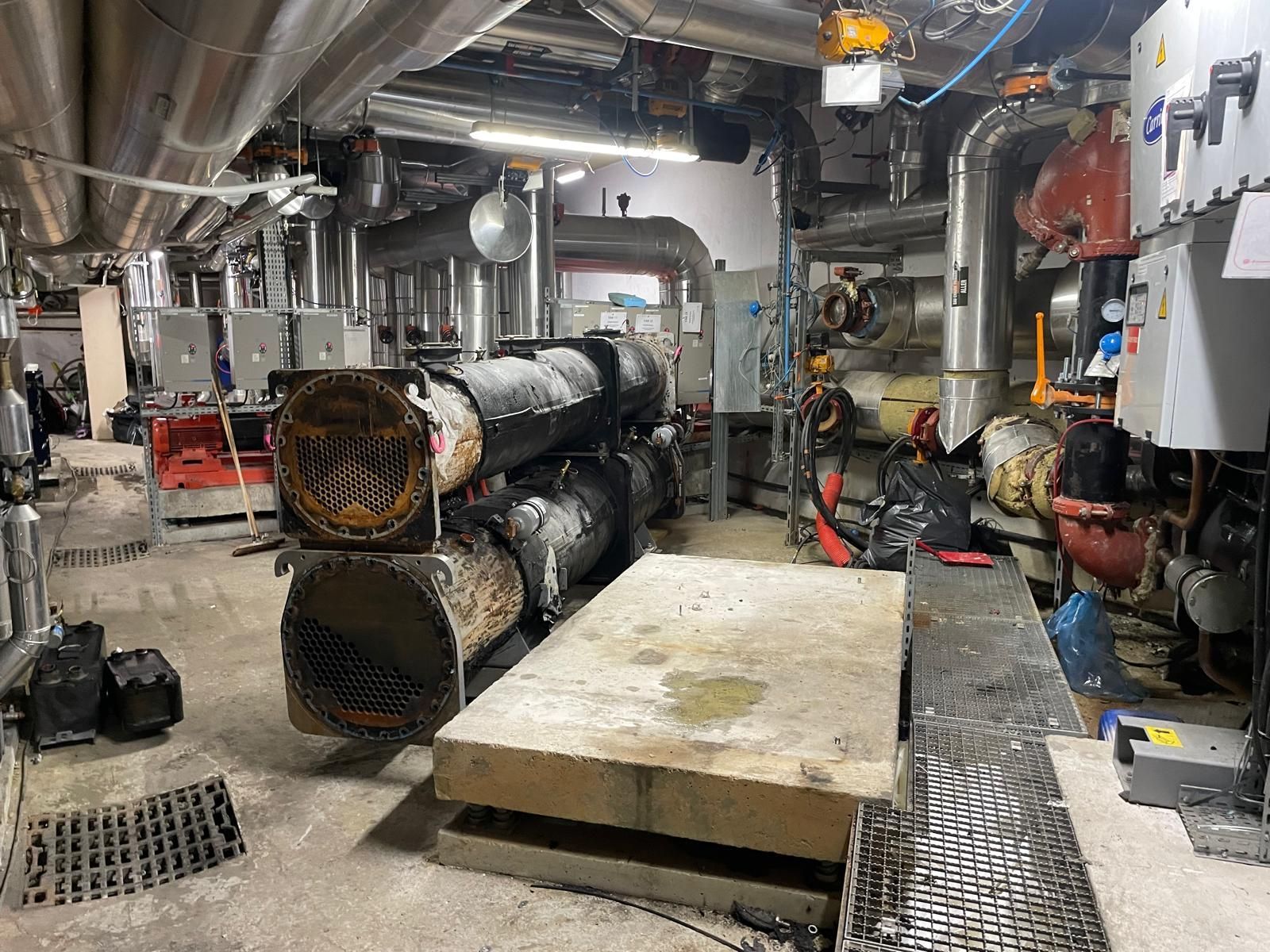 Équipements industriels dans une chaufferie, avec de grosses canalisations, des conduits et une plateforme surélevée en béton