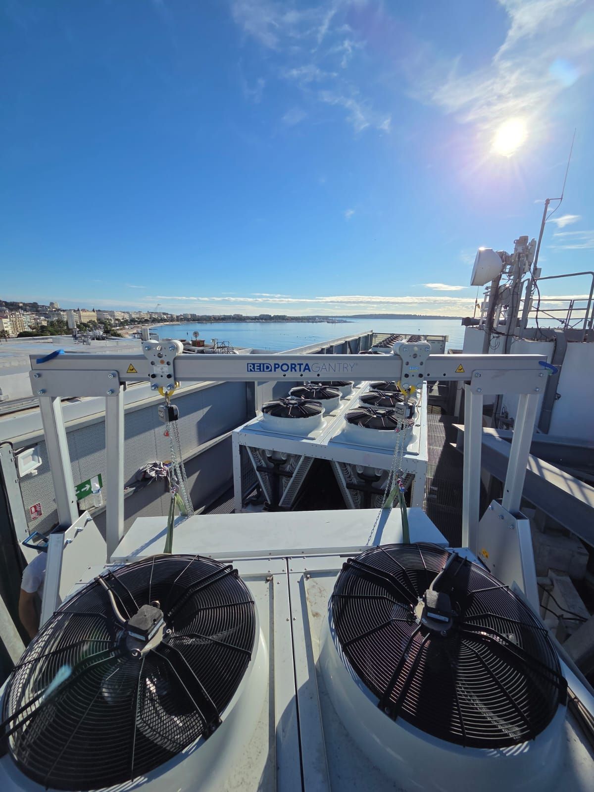 Ventilateurs de refroidissement sur un toit, surplombant un port enneigé sous un ciel d’un bleu éclatant
